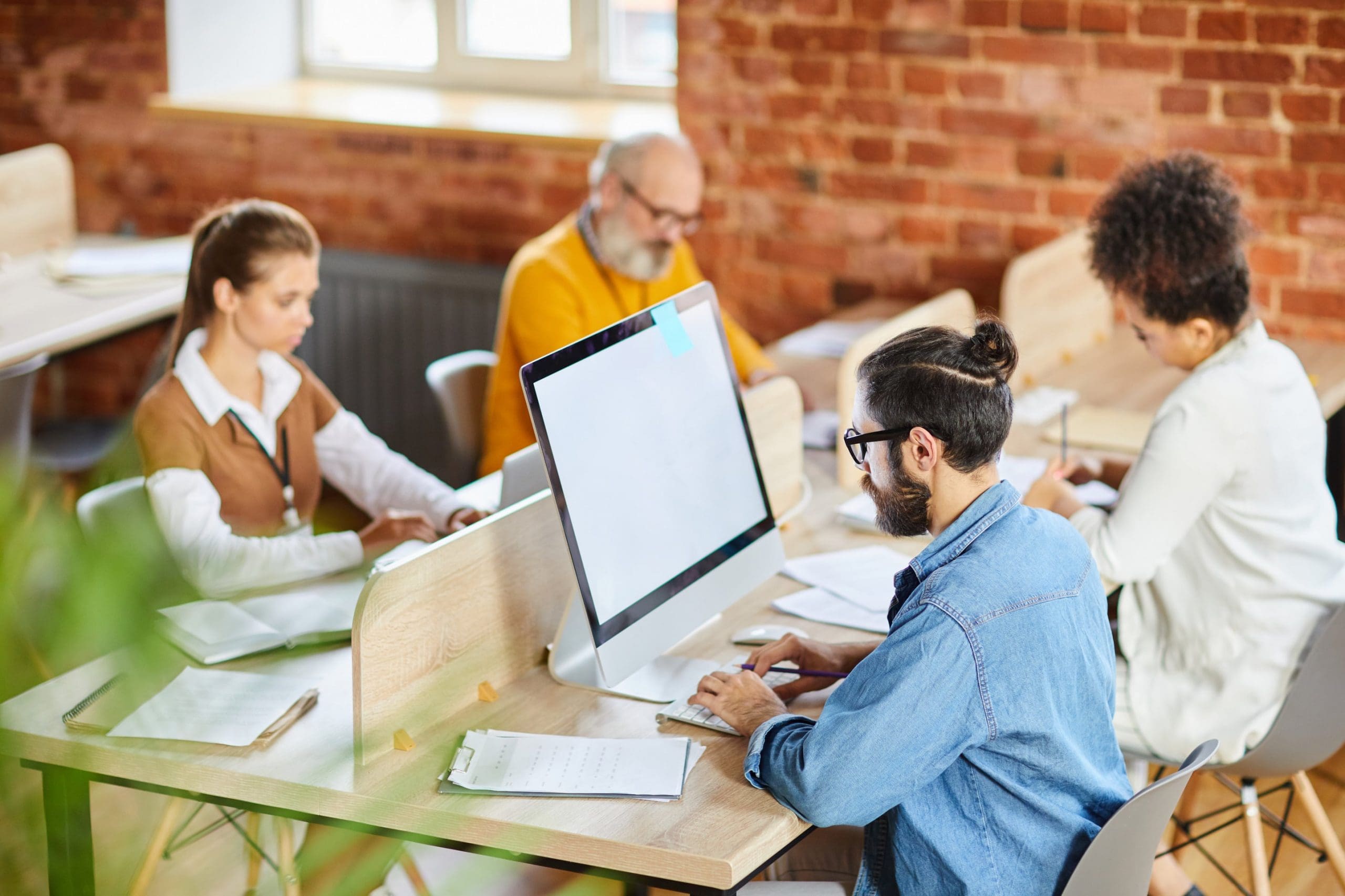 a group of people sitting at a table working on computers.