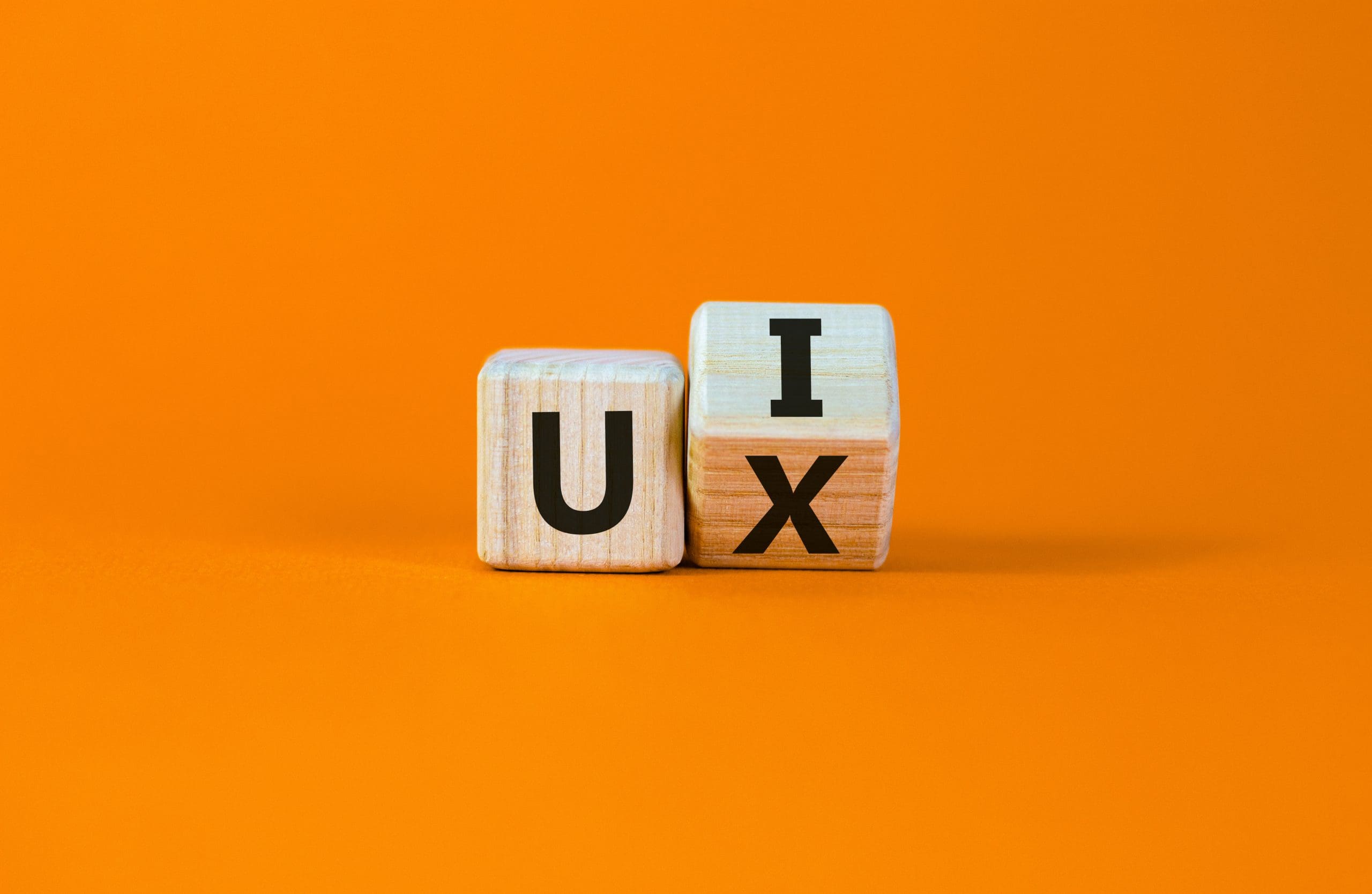 Two wooden blocks with the word ux on an orange background.