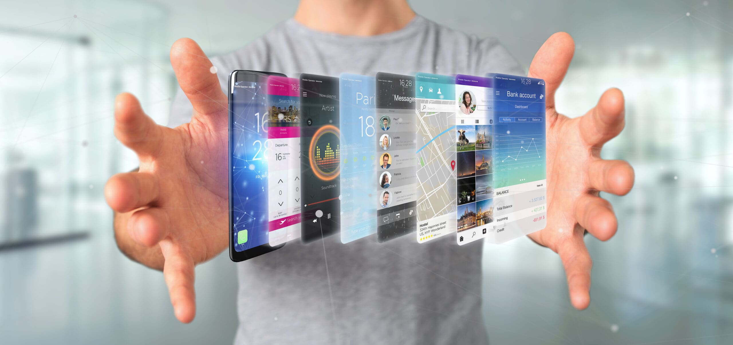 A person in a grey shirt is holding out their hands. Between their hands, there are graphics of a smartphone and various digital displays including apps for music, social media, calendar, maps, bank, and messages, creating a holographic effect.